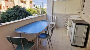 a blue table and chairs on a balcony with a kitchen at Blu Celeste - by AP Apartment in Baia Verde