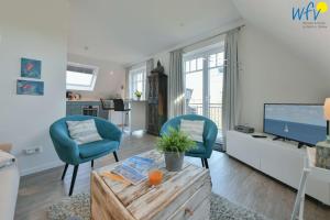 a living room with two blue chairs and a tv at Bootshaus in den Duenen - 4 "Ferienwohnung Duenenkoje" in Wangerooge