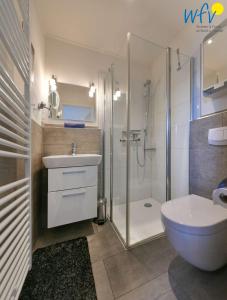 La salle de bains est pourvue d'une douche, d'un lavabo et de toilettes. dans l'établissement Bootshaus in den Duenen - 4 "Ferienwohnung Duenenkoje", à Wangerooge
