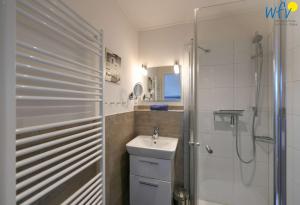 a white bathroom with a sink and a shower at Bootshaus in den Duenen - 4 "Ferienwohnung Duenenkoje" in Wangerooge +28 photos