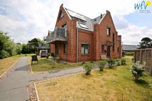 a brick house with a balcony on a yard at Bootshaus in den Duenen - 4 "Ferienwohnung Duenenkoje" in Wangerooge