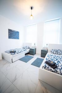ein weißes Zimmer mit 3 Betten und 3 Teppichen in der Unterkunft Apartment Hafenarbeiter in Bremerhaven