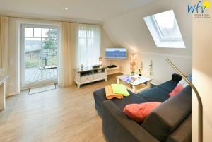 a living room with a couch and a large window at Bootshaus in den Duenen - 4 "Ferienwohnung Sonnendeck" in Wangerooge