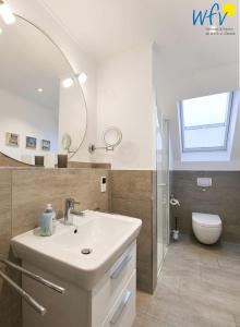 a bathroom with a sink and a mirror and a toilet at Bootshaus in den Duenen - 4 "Ferienwohnung Sonnendeck" in Wangerooge