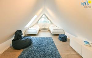 a attic room with two beds and a rug at Bootshaus in den Duenen - 4 "Ferienwohnung Sonnendeck" in Wangerooge