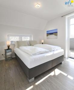 a large white bed in a bedroom with a window at Bootshaus in den Duenen - 5 Bootshaus in den Duenen Wangerooge - 5 in Wangerooge