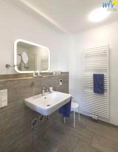 ein Badezimmer mit einem weißen Waschbecken und einem Spiegel in der Unterkunft Bootshaus in den Duenen - 5 Bootshaus in den Duenen Wangerooge - 5 in Wangerooge