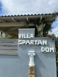 ein Schild an der Seite eines Gebäudes mit einem spartanischen Schild in der Unterkunft Villa Spartandom in Gerakini