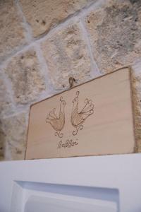 a sign with two roosters on a brick wall at Bobboi in Cagliari +14 photos