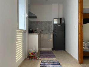 La cuisine est équipée d'un réfrigérateur noir et d'un évier. dans l'établissement cozy apartment, à La Marsa