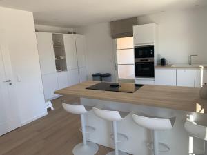 a kitchen with white cabinets and a counter with stools at Les Collines de Saint-André in Saint-André-de-Cruzières