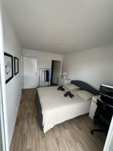 a bedroom with a large white bed with two shoes on it at Appartement F2 proche Paris CDG/parc expos/RER B in Sevran