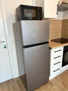 a refrigerator with a microwave on top of it in a kitchen at Appartement F2 proche Paris CDG/parc expos/RER B in Sevran