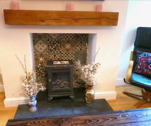 a fireplace in a living room with two vases at Chic 2-bedroom townhouse in vibrant Abergavenny in Abergavenny