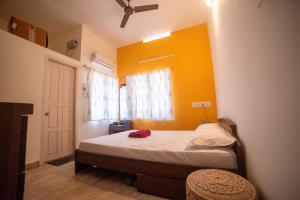 um quarto com uma cama com uma parede amarela em Tranquil Homestay em Mangalore
