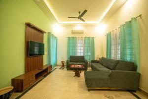 uma sala de estar com um sofá e uma televisão de ecrã plano em Tranquil Homestay em Mangalore