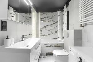 La salle de bains blanche est pourvue d'un lavabo et de toilettes. dans l'établissement Apartament 666 ogród Stare Miasto, à Szczecin
