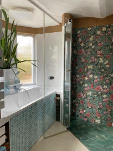 a bathroom with a tub and a shower with floral wallpaper at Ferienhaus Lotte Havelland in Götz