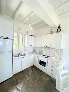a white kitchen with white cabinets and a sink at Aggeliki's Cycladic Villa by Hostandros in Batsi