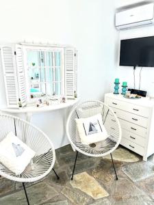 a room with two chairs and a desk with a tv at Aggeliki's Cycladic Villa by Hostandros in Batsi