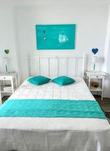 a white bed with two blue pillows in a bedroom at Aggeliki's Cycladic Villa by Hostandros in Batsi