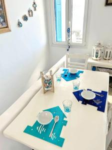 a white table with plates and silverware on it at Aggeliki's Cycladic Villa by Hostandros in Batsi +17 photos
