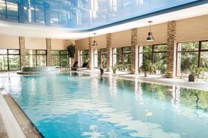 a large swimming pool in a building with windows at Sodeliškių dvaro sodyba in Sodeliškiai