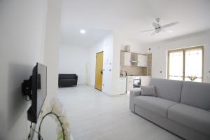 een witte woonkamer met een bank en een keuken bij Il nascondiglio in San Ferdinando di Puglia
