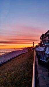 a beach at sunset with a lighthouse in the distance at meergut HOTELS in Kühlungsborn