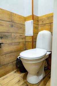 a toilet in a bathroom with a wooden wall at Evergreen Hostel in Almaty