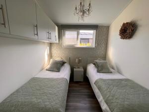 two twin beds in a small room with a window at Vakantie Villa Markermeer in Bovenkarspel
