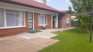 a brick house with a green lawn in front of it at 3 Lavenders apartment in Bloemfontein