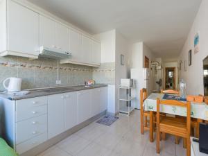 eine Küche mit weißen Schränken und einem Tisch mit Stühlen in der Unterkunft Apartamento Pura vida con WIFI Playas y compras in Vecindario