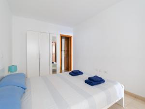 ein weißes Schlafzimmer mit einem Bett mit blauen Kissen darauf in der Unterkunft Apartamento Pura vida con WIFI Playas y compras in Vecindario