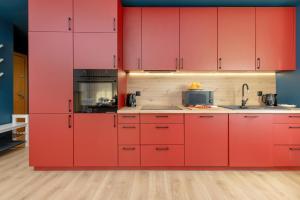 una cocina con armarios rojos y fregadero en Beautiful & Spacious 2 Bedroom Apartment Mickiewicza by Renters, en Puck