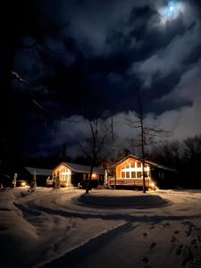 a house in the snow at night with the moon at Chill Village in Biei