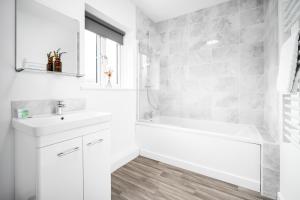 a white bathroom with a tub and a sink at New Modern 2 Bedroom Apartment - WIFI & Netflix - Secure Parking - 27AC in Sleightholme