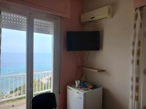 a room with a television and a balcony with the ocean at FIORE ROOMS in Akrotiri