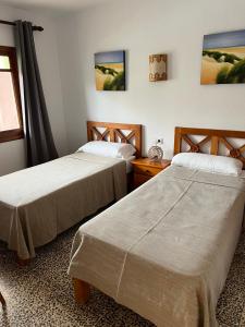two beds sitting in a room with a window at Apartamentos Colomar in Es Figueral Beach