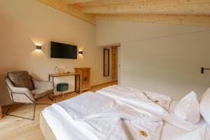 een slaapkamer met een wit bed en een stoel bij Haus Jausern in Saalbach Hinterglemm