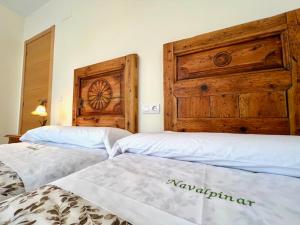 - une chambre avec 2 lits et une tête de lit en bois dans l'établissement Navalpinar, à Navalmanzano