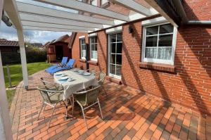 eine Terrasse mit einem Tisch und Stühlen auf einem Backsteingebäude in der Unterkunft Nordseeferien Nessmersiel in Neßmersiel