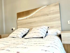 - une chambre avec un lit doté d'une tête de lit en bois et d'oreillers dans l'établissement Navalpinar, à Navalmanzano