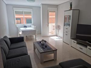 uma sala de estar com um sofá, uma televisão e uma mesa em PUERTO BENICARLÓ em Benicarló
