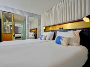 a bedroom with two beds with white pillows at INK Hotel Amsterdam - MGallery Collection in Amsterdam