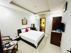 a bedroom with a bed and a table and a tv at REDFLOWER HOTEL in Ho Chi Minh City