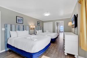 two beds in a hotel room with white and blue at Beachfront Luxury Condo w Private Balcony in Myrtle Beach