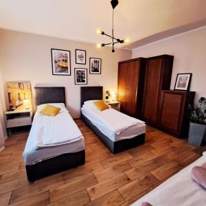 a bedroom with two beds and a wooden floor at Apartament pod Miastem in Szamotuły