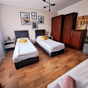 two beds in a room with wooden floors at Apartament pod Miastem in Szamotuły