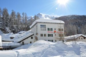 un hotel en la nieve frente a un edificio en Hotel Seraina, en Sils-Maria